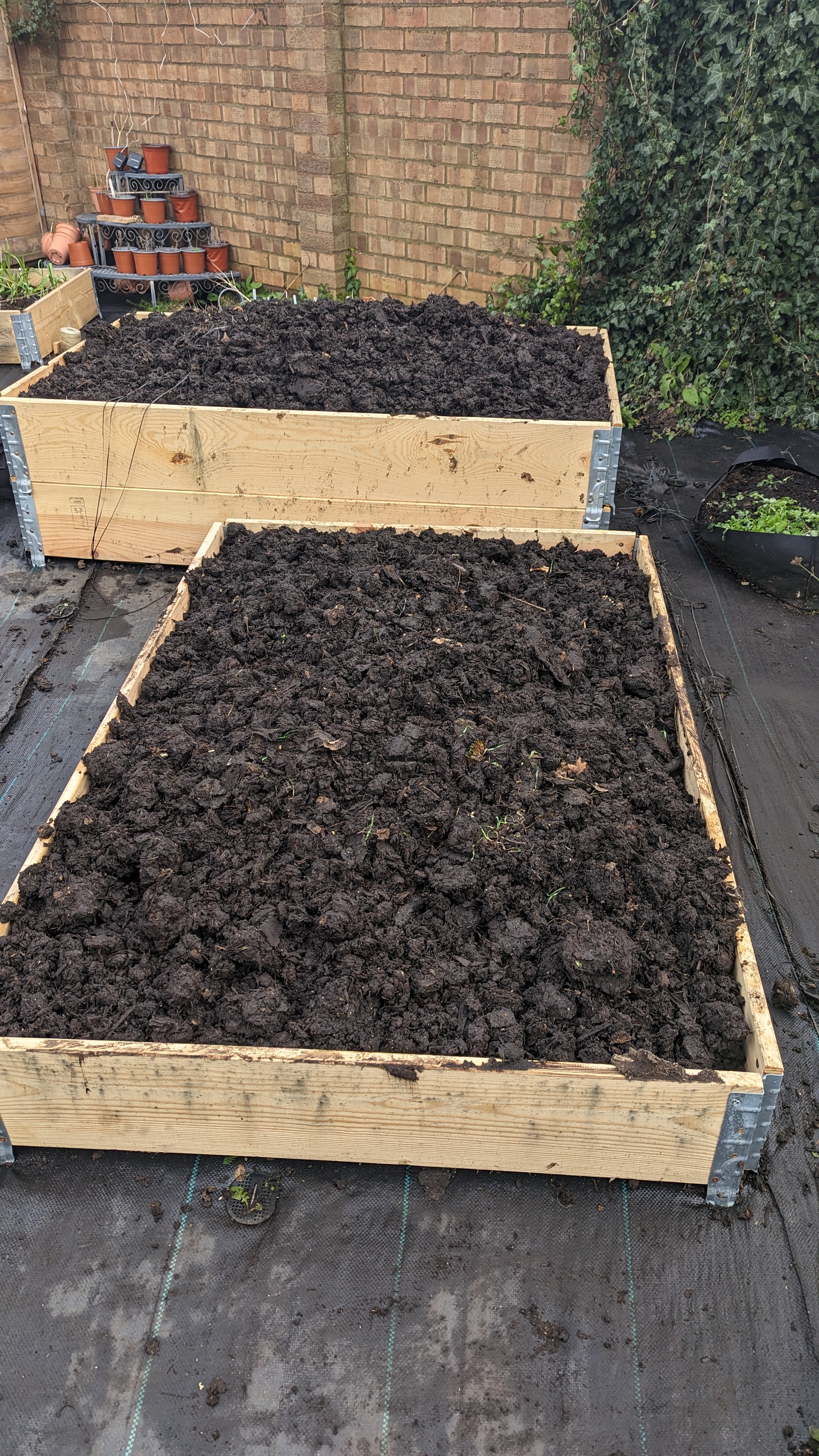 Two raised beds made from pallet collars, one taller than the other, both heaped with compost
